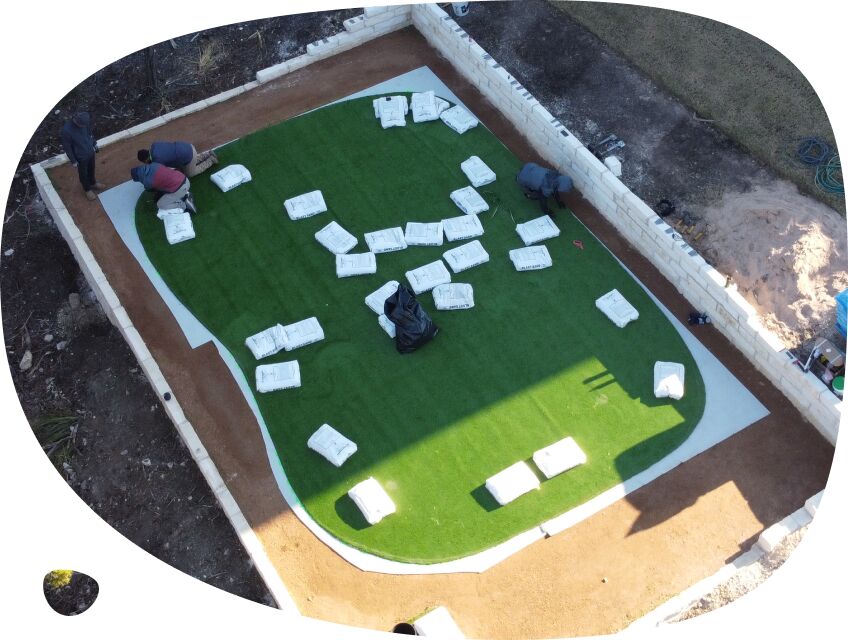 Synthetic grass installation process of laying out grass and border trimming.